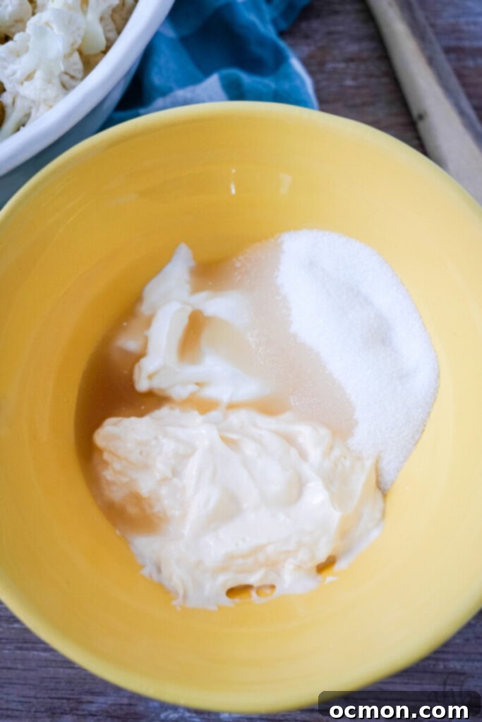 Amish-Style Creamy Broccoli and Cauliflower Salad 5 A close-up shot of vinegar, sour cream, granulated sugar, and mayonnaise being whisked together in a bowl to create the creamy dressing.