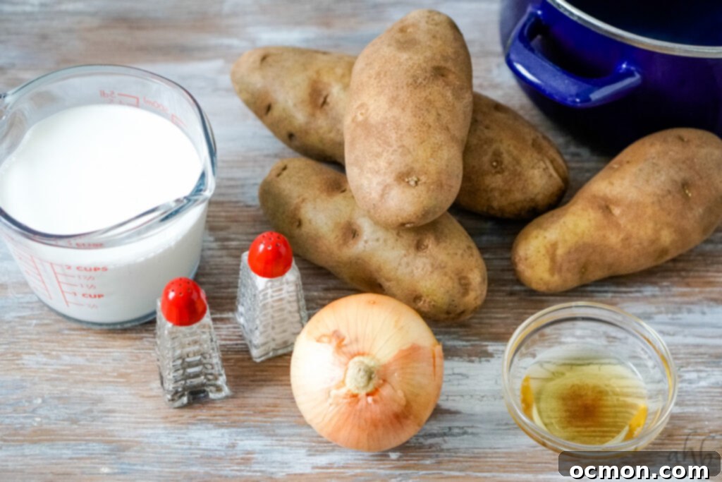 A kitchen counter setup with all the essential ingredients for 4-ingredient potato soup: a measuring cup with 2 cups of half and half, salt and pepper shakers, a small yellow onion, a bowl of rendered bacon grease, four large russet potatoes, and a blue stockpot, ready for cooking.