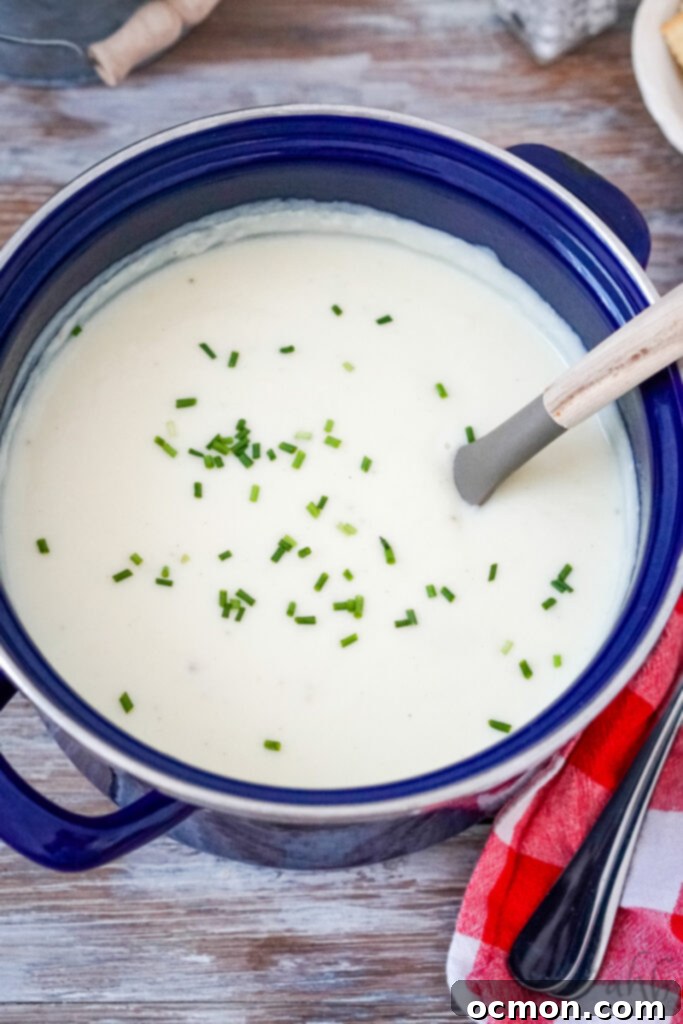 The blue stockpot is now brimming with rich, creamy 4-ingredient potato soup, garnished elegantly with freshly chopped chives, showcasing its readiness for serving.