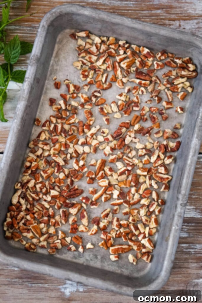 A small sheet pan of evenly toasted pecan pieces, golden brown and fragrant, freshly removed from the oven.