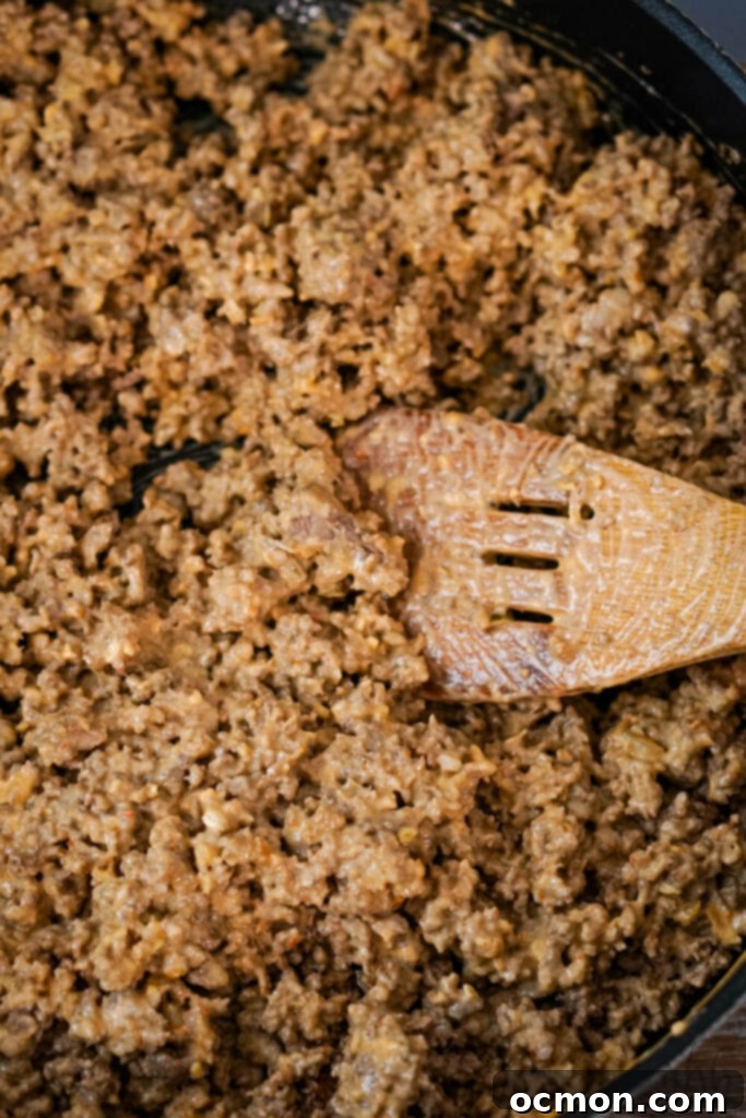 Loaded Big Mac Tater Tot Bake 6 Browned ground beef being stirred with a wooden spoon.