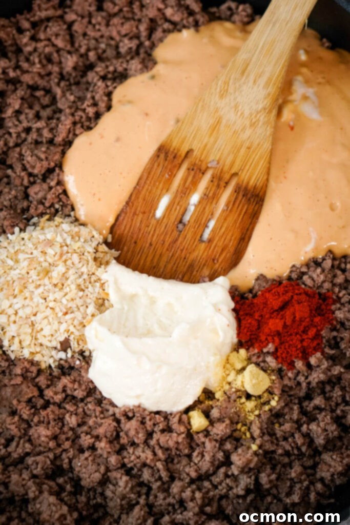 Loaded Big Mac Tater Tot Bake 7 A wooden spoon combines browned ground beef, thousand island dressing, dried minced onion, mayo, dried ground mustard, and paprika.