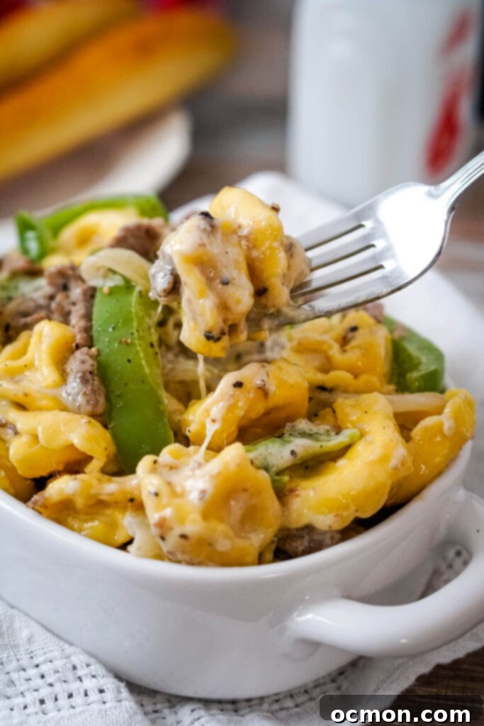 Cheesesteak Stuffed Tortellini 2 A serving of Philly Cheesesteak Tortellini in a white dish being served with a fork.