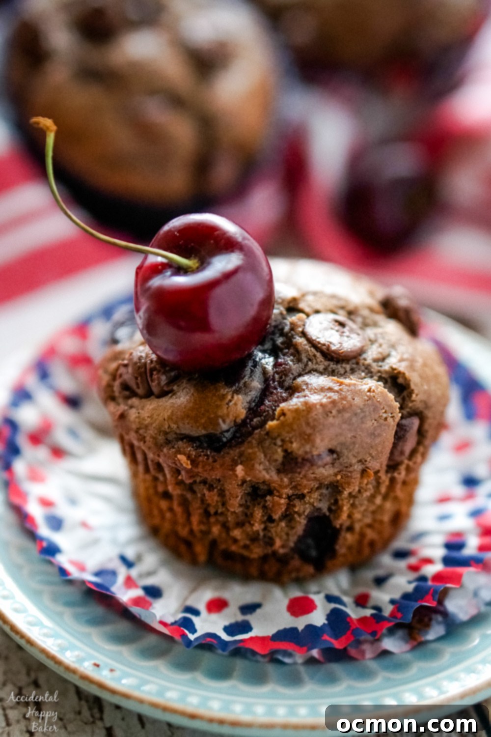 A close-up of a perfectly baked, moist Chocolate Cherry Muffin, showcasing the generous distribution of chocolate chips and juicy cherries within its rich, dark crumb, inviting a delicious bite.